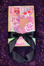 Beautiful book wrapped in light coral, pink, and orange hues and wrapped in a beautiful black satin bow, adorned with goodies.