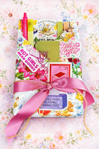 Colorful, floral wrapping paper around a book with cheerful, fun stickers and goodies.